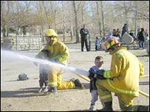 Fireman showing child how to use hose