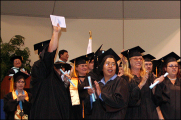 Graduates cheering for their families and friends who helped them get their degrees.