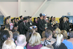 The graduates stand, ready to receive their diplomas of graduation.